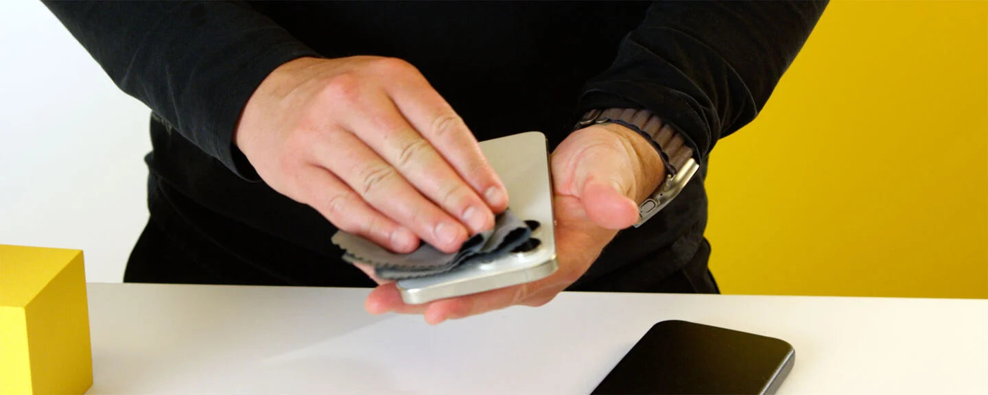 Person shuffling a deck of cards with a yellow cube and phone on a white surface.