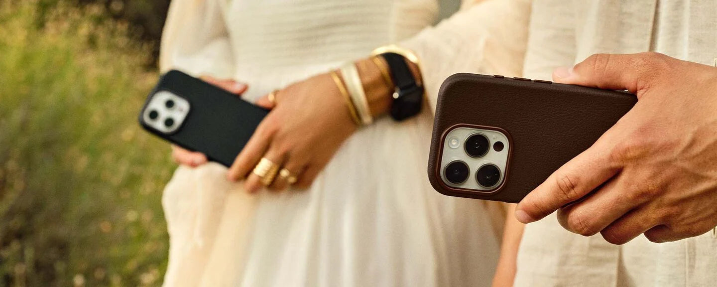 Two people holding smartphones with a blurred natural background