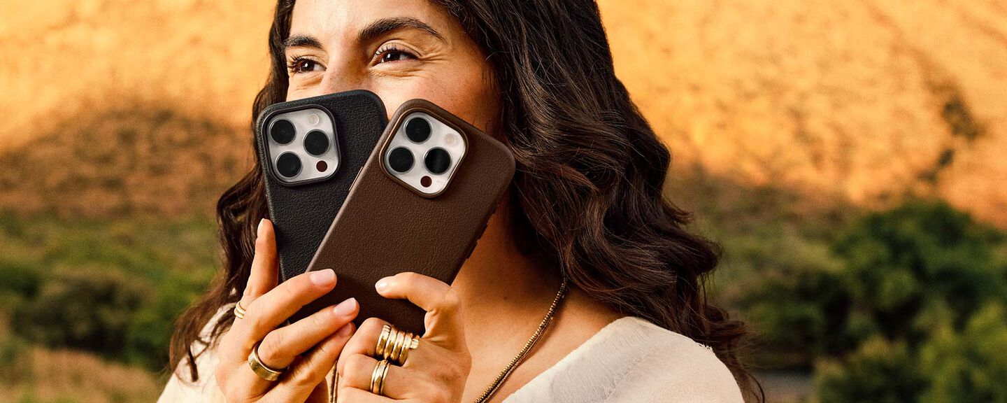 Person holding two smartphones with a scenic background