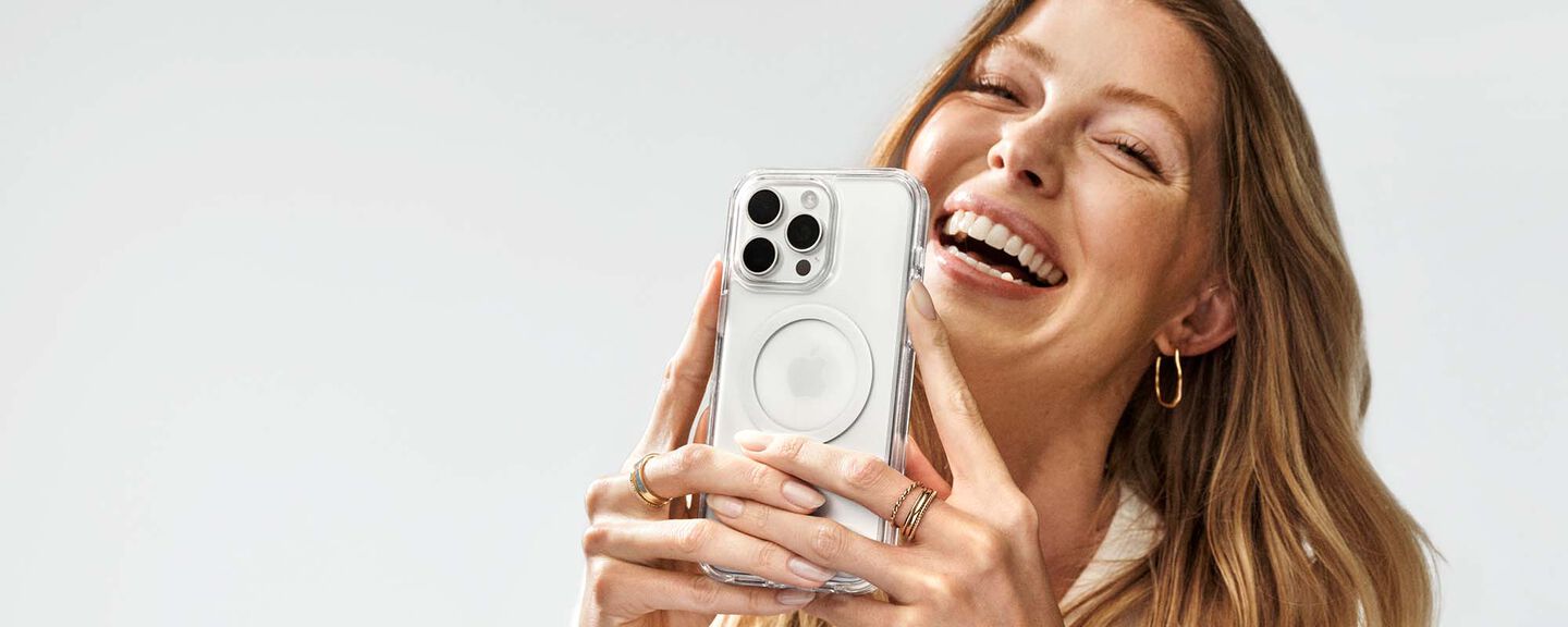 Woman holding a smartphone with a clear case against a light background