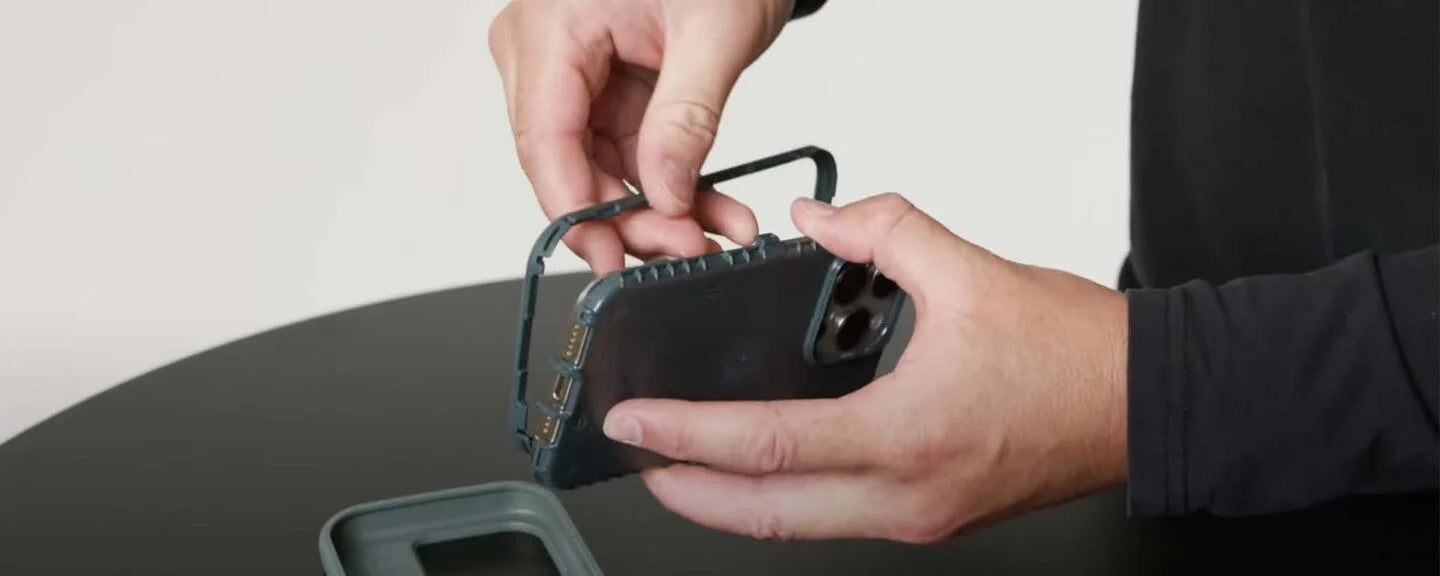 Person holding a small electronic device with a screen on a dark surface
