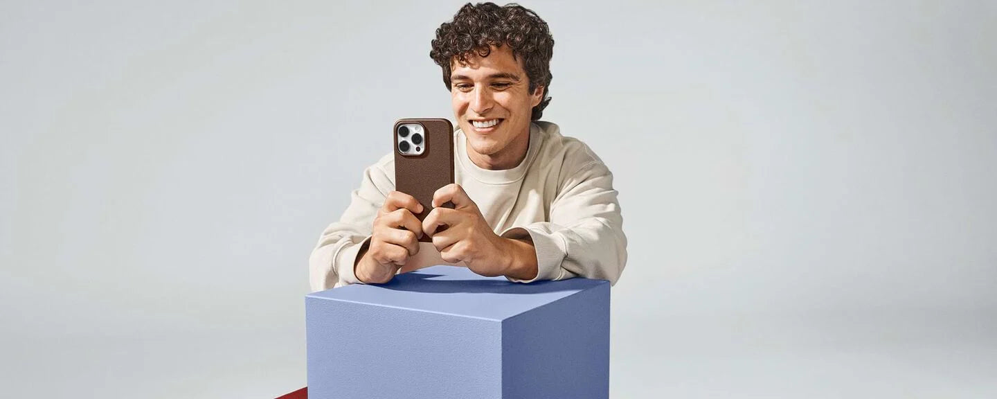Man holding a smartphone on a blue box against a light gray background