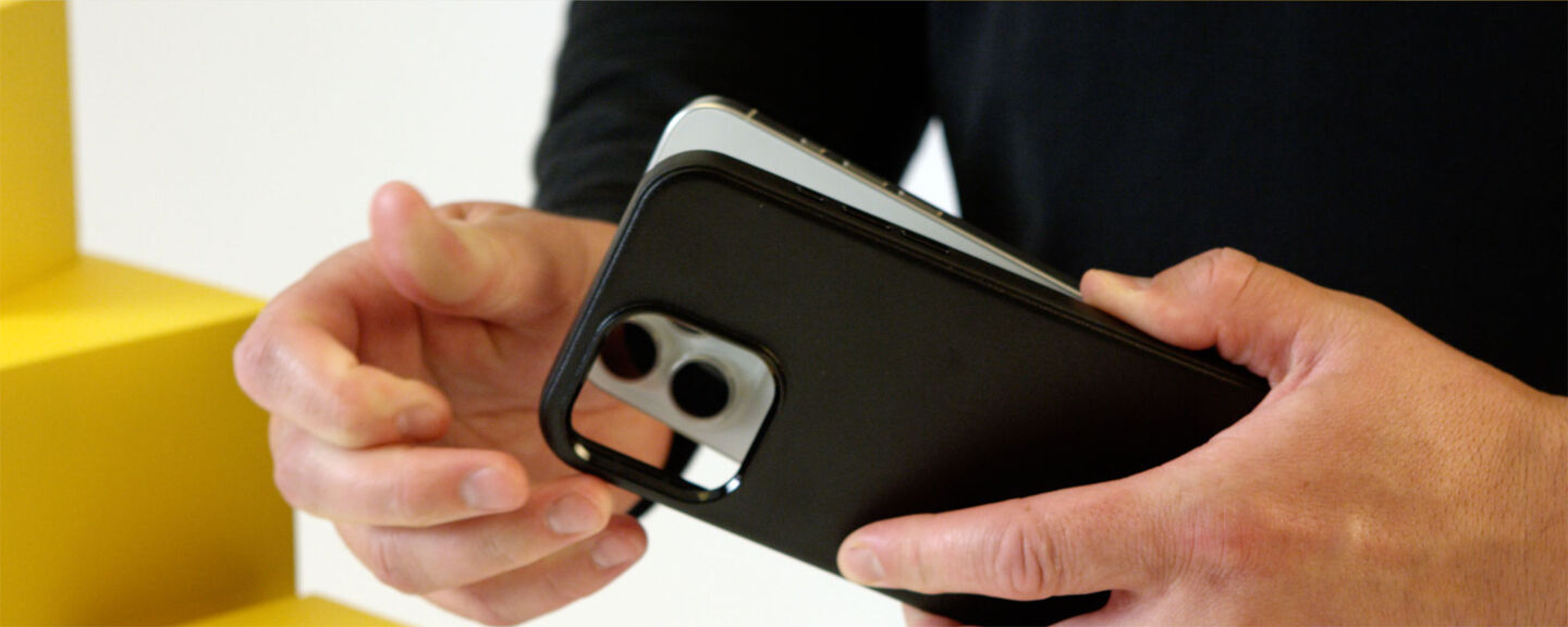 Person holding a smartphone with a black case against a white background