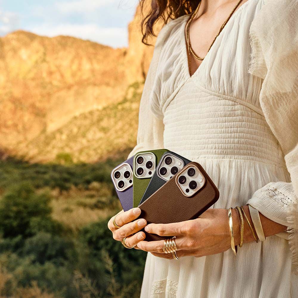 Person holding three smartphones with a scenic background