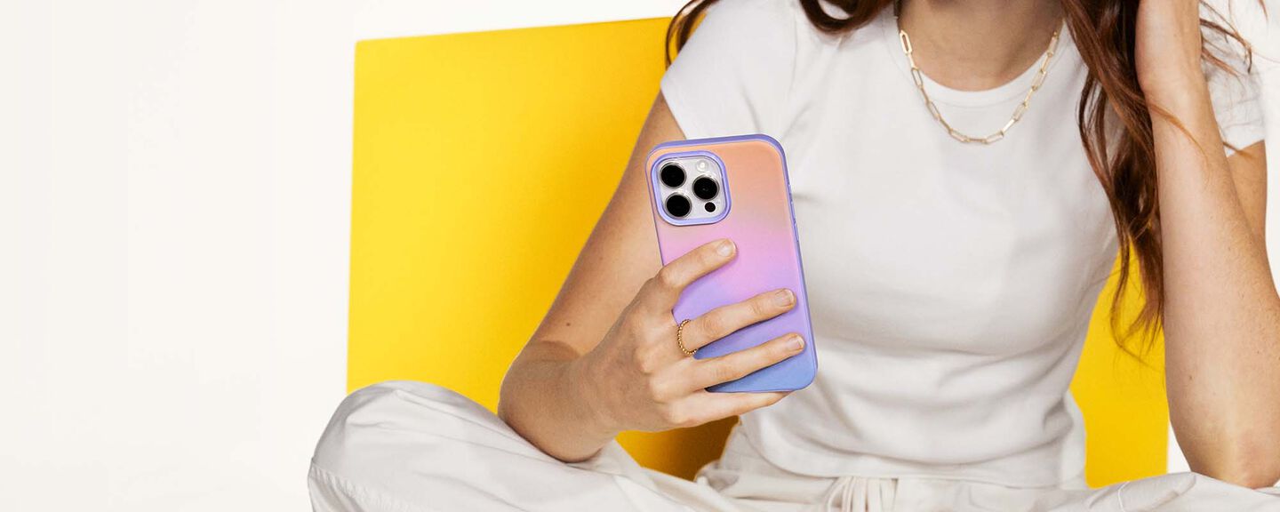 Person holding a phone with a colorful case against a yellow background